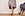 Eine Frau trägt Kompressionsstrümpfe. Sie steht neben einem Schaukelstuhl.