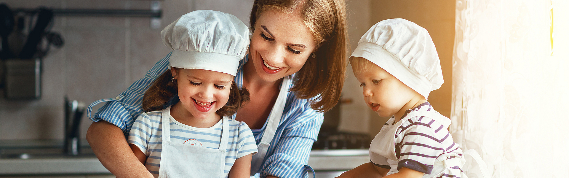 Die Haushaltshilfe der Familie bereitet mit den Kindern das Essen vor.