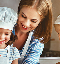 Mutter mit zwei Kindern bereitet ein gesundes Mittagessen vor. Leider gibt es auch Kinder die zu dick sind. Für diese gibt es das Angebot beim RICHTIG ESSEN – Gewichts-Coaching KOMBIPLUS.