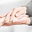 Die Hände einer jungen Person umfassen eine Hand einer älteren Person.