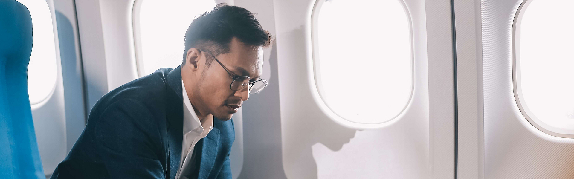 Junger gutaussehender Geschäftsmann mit Notizbuch sitzt in einem Flugzeug.