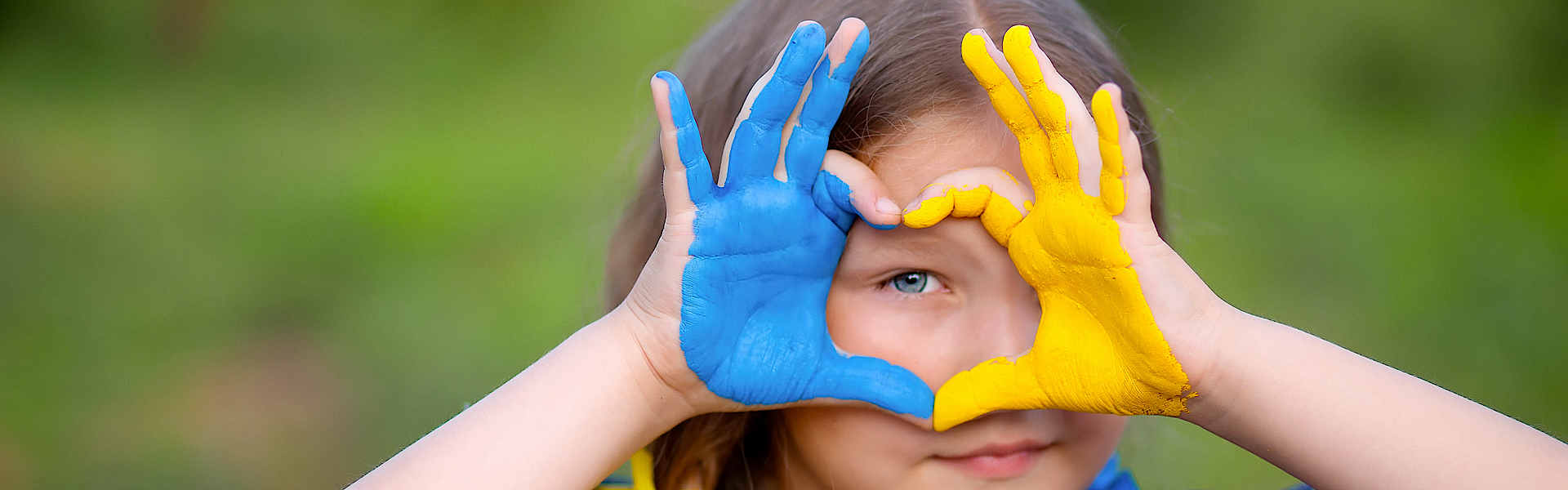 Kleines Mädchen zeigt ihre Hände in Herzform in der Ukraine Flagge Farbe - gelb und blau.