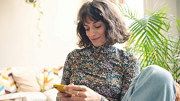 Junge Frau nutzt mit ihrem Smartphone die digitalen Services der mhplus.