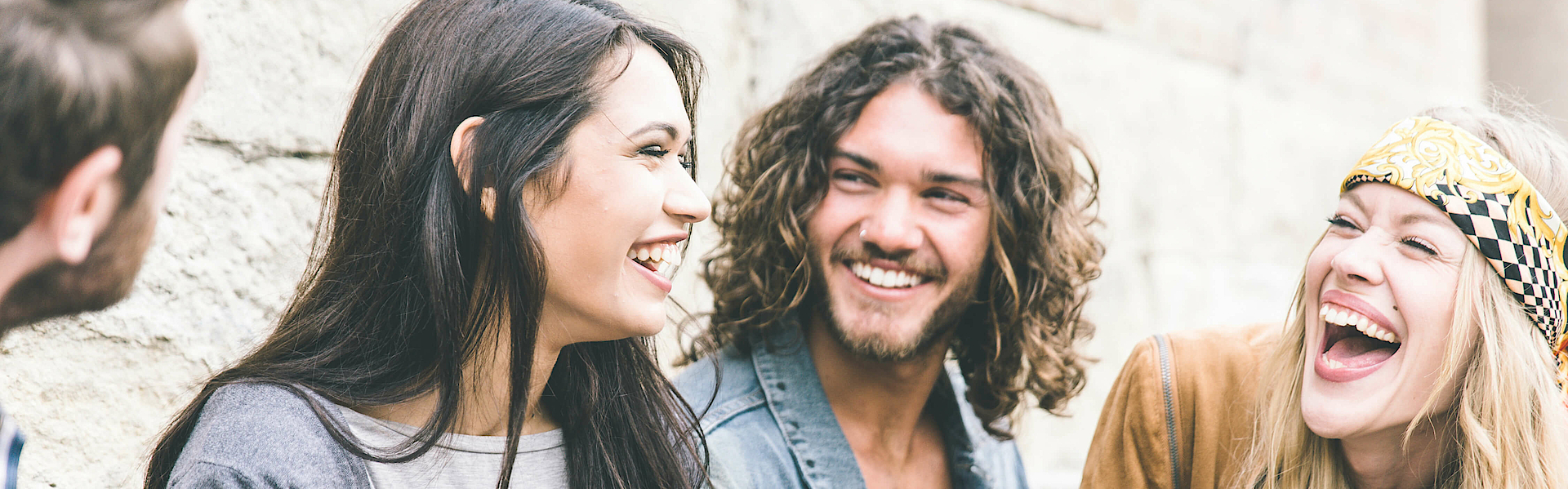 Gruppe von vier Freunden, die laut draußen lachen, es herrscht eine gute und positive Stimmung.