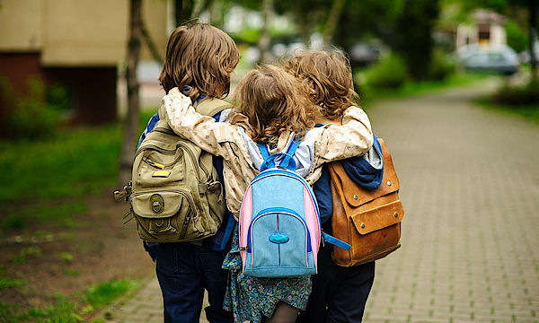 Drei Kinder laufen gemeinsam auf der Straße.