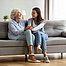 Zwei Frauen, die Spaß beim Unterhalten haben, sitzen auf dem Sofa im modernen Wohnzimmer. 