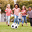 Zur Stärkung des Immunsystems bei Kindern rennen ein paar Mädchen und Jungen einem Fußball hinterher