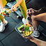 Top-Blick asiatische Mann und Frau gesund essen Salat nach der Übung im Fitnessraum. Zwei Sportler essen zusammen Salat für Gesundheit. Selektiver Fokus auf Salatschüssel zur Verfügung.