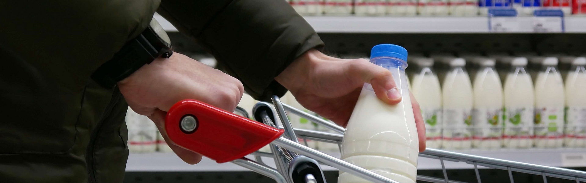 Kunde im Supermarkt mit Milchflasche