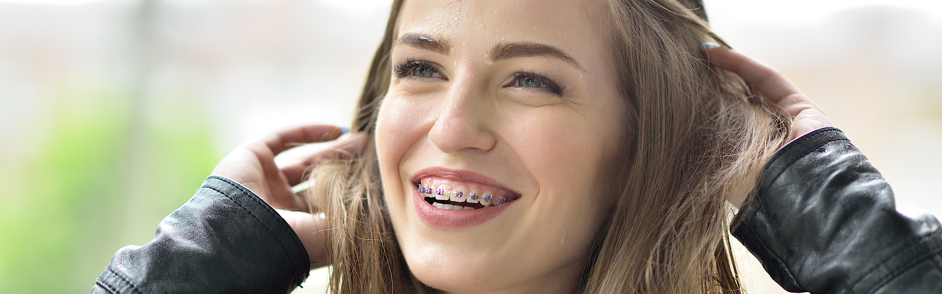 Lachende junge Frau. Sie hat beim lachen den Mund geöffnet und man sieht die Brackets auf ihren Zähnen.