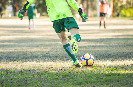 Der Fußballspieler auf dem Spielfeld versucht den Fußball wegschießen.