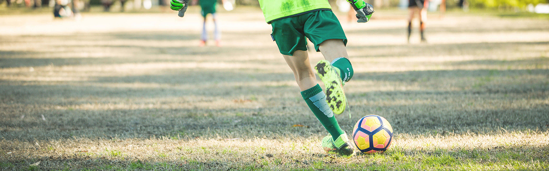 Der Fußballspieler auf dem Spielfeld versucht den Fußball wegschießen.