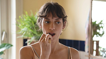 Frau steht im Badezimmer und putzt sich die Zähne.