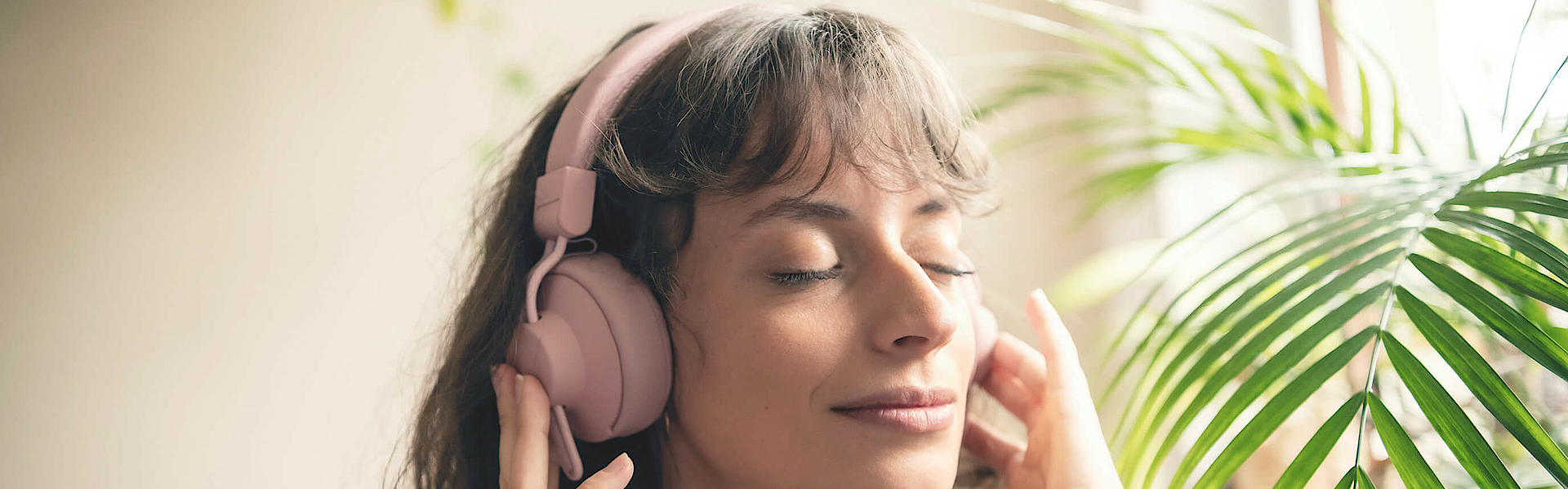Frau hört über Kopfhörer Musik, sie hat die Augen geschlossen und ist entspannt.