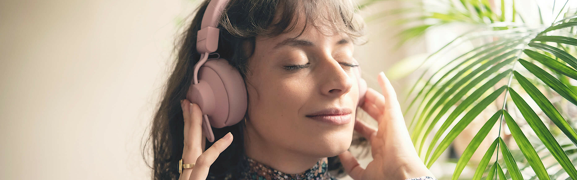 Frau hört über Kopfhörer Musik, sie hat die Augen geschlossen und ist entspannt.