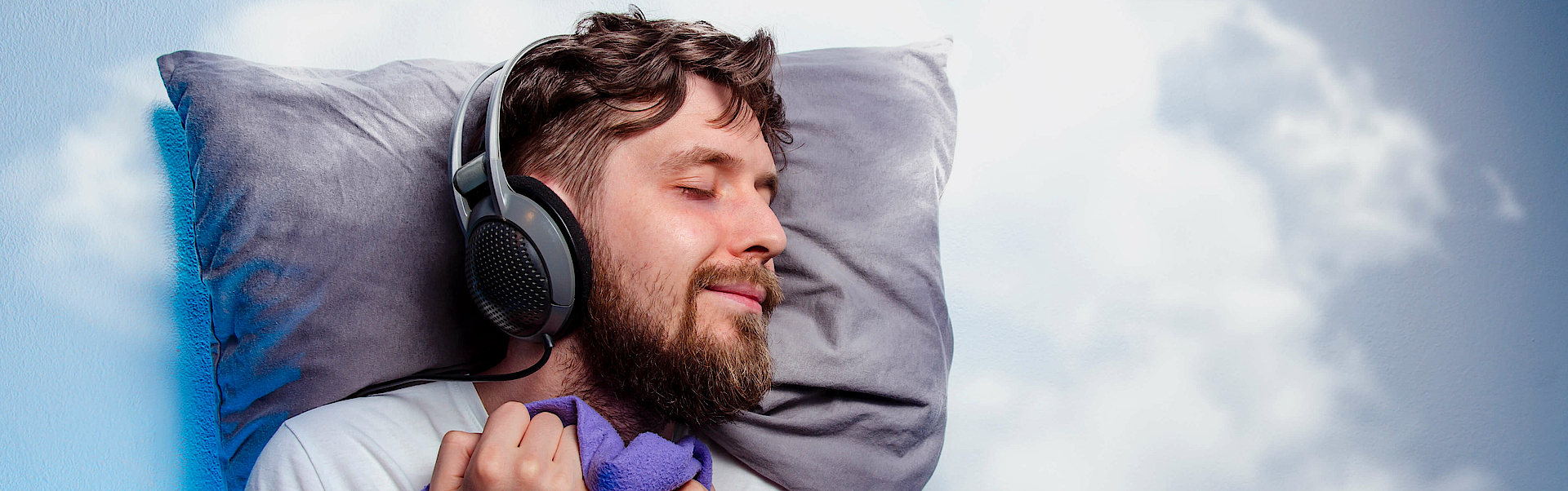Zu sehen ist ein träumender Mann mit Bettwäsche auf einer Wolke und Kopfhörern.