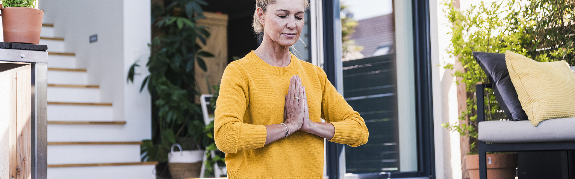 Frau auf einer Terasse übt eine Yoga-Position