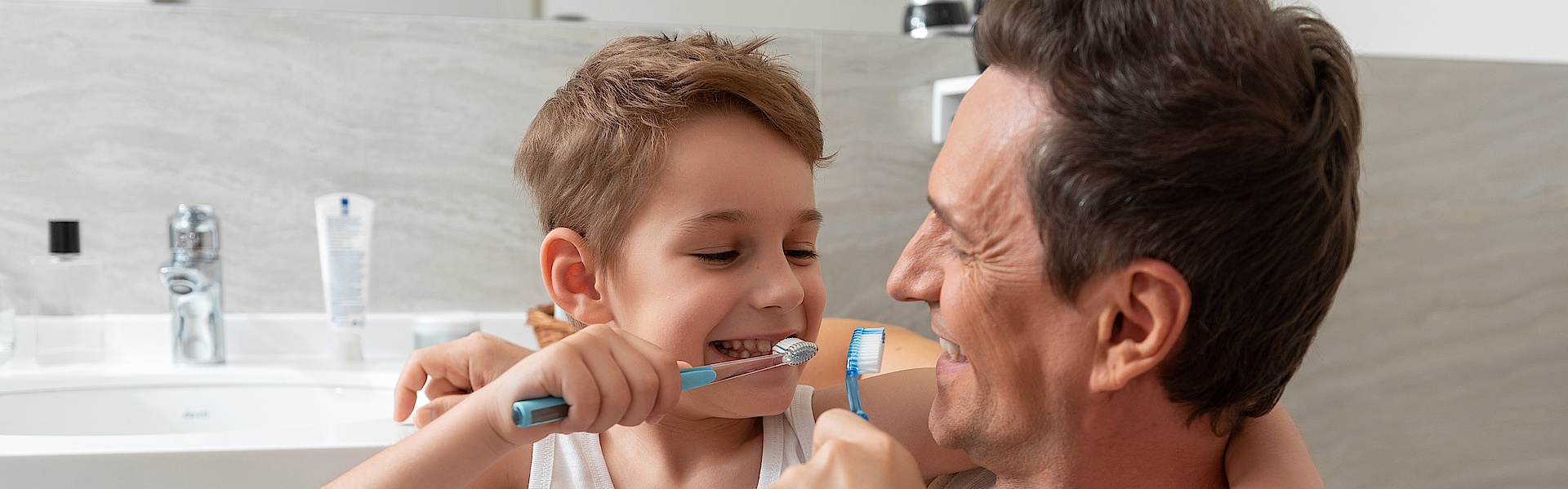 Ein Mann und ein Kind beim Putzen gemeinsam die Zähne . Die Beiden sind im Badezimmer.