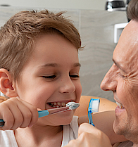 Ein Mann und ein Kind beim Putzen gemeinsam die Zähne . Die Beiden sind im Badezimmer.