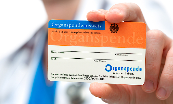 Mann hält einen Organspende-Ausweis in der Hand.