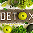 Das Wort Detox ist aus Samen gelegt. Drum herum liegen Äpfel, Trauben und andere Lebensmittel, die angeblich entgiftend wirken.