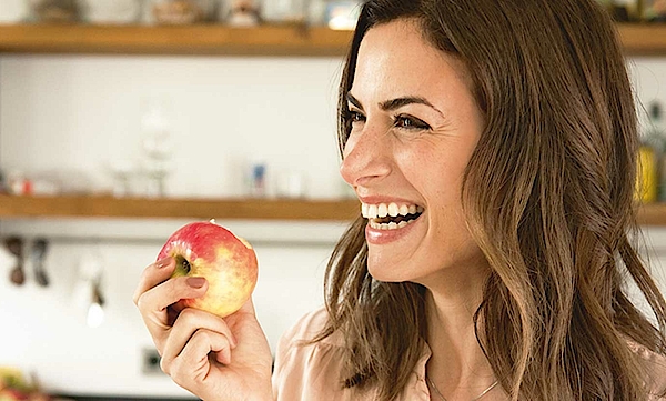 Eine Frau hält einen Apfel in der Hand.