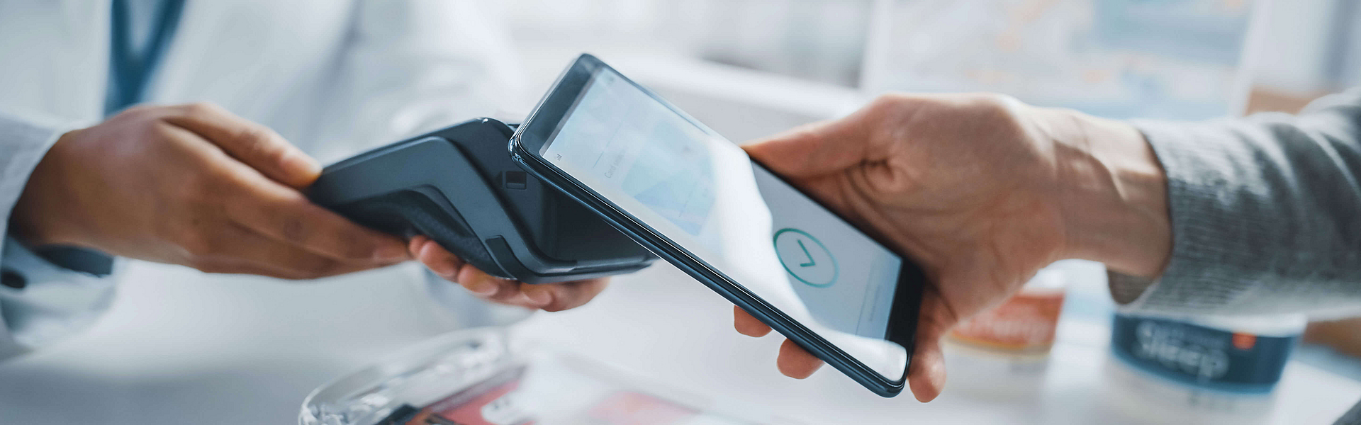 Ein Kunde steht in einer Apotheke. Er löst per Smartphone ein e-Rezept ein.