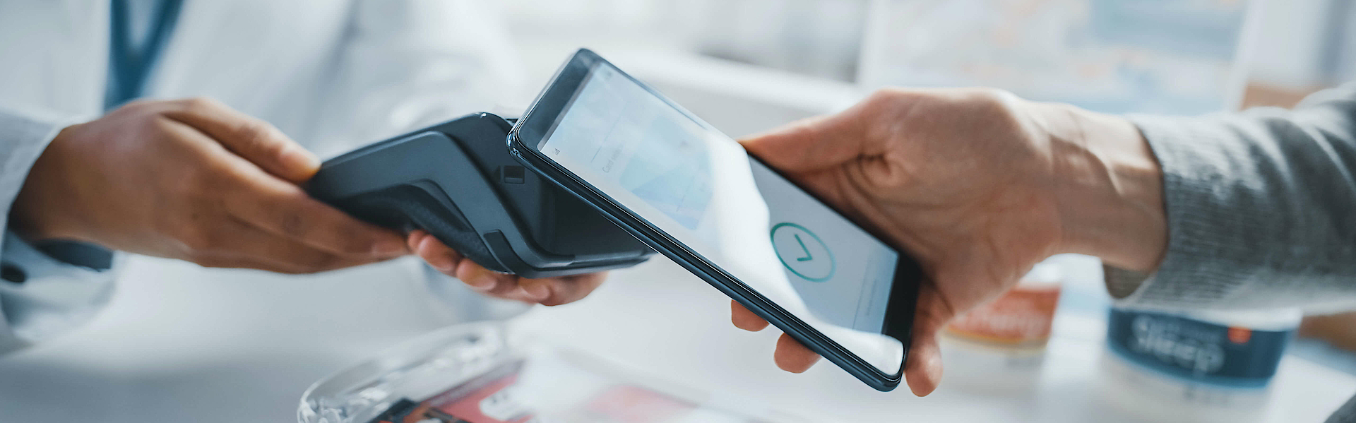 Ein Kunde steht in einer Apotheke. Er löst per Smartphone ein e-Rezept ein.