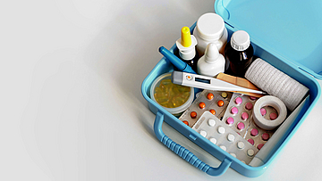 Auf dem Tisch steht eine Box mit Medikamenten, Fieberthermometer und vieles mehr.