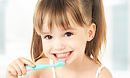 Nahaufnahme eines glücklichen kleinen Mädchens, das sich die Zähne mit einer Kinderzahnbürste putzt.