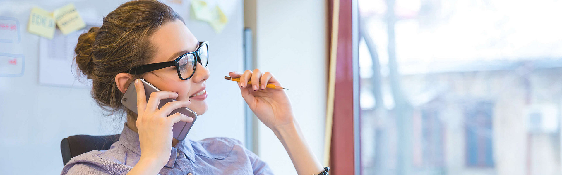 Geschäftsfrau mit Brille telefoniert mit dem Handy.