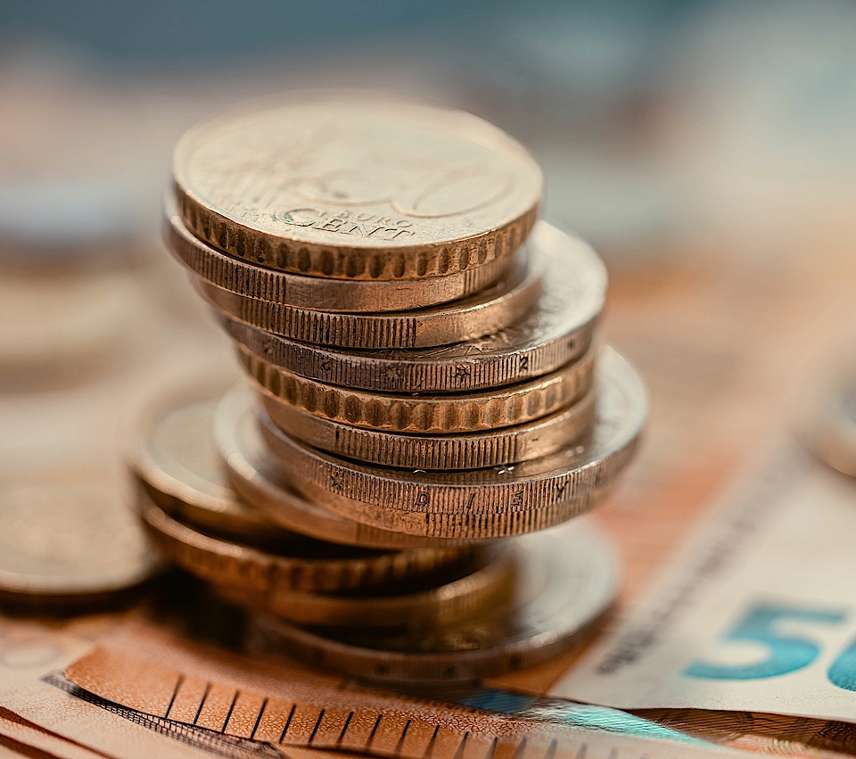 Münzen gestapelt auf Euro-Scheine.