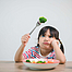 Ein kindlicher Picky Eater schaut missmutig auf eine Gabel mit Brokkoli, 
