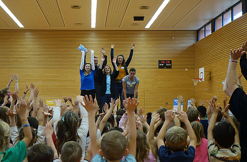 Vier Mitarbeiter von der mhplus und Stadt Ludwigsburg animieren Gruppe von Kindergartenkindern in Sporthalle beim Aktionstag von 20 Jahre MINIFIT