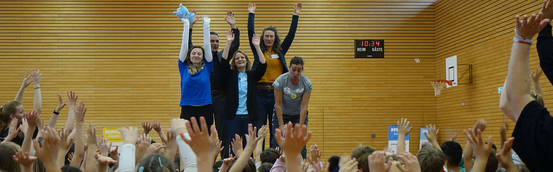 Vier Mitarbeiter von der mhplus und Stadt Ludwigsburg animieren Gruppe von Kindergartenkindern in Sporthalle beim Aktionstag von 20 Jahre MINIFIT