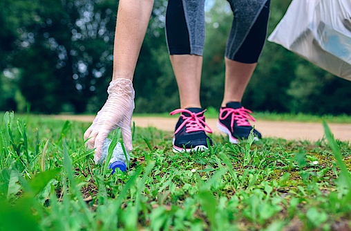 Eine Person im Laufkleidung sammelt Müll auf einer Weise, der Trend wird als Plogging bezeichnet