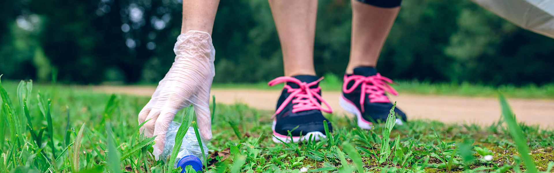 Eine Person im Laufkleidung sammelt Müll auf einer Weise, der Trend wird als Plogging bezeichnet
