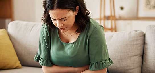 Geht es dem Darm nicht gut, wirkt sich das auf das Immunsystem aus Frau verschränkt schmerzhaft die Arme vor ihrem Bauch, weil ihr Darm und somit das Immunsystem gestört sind