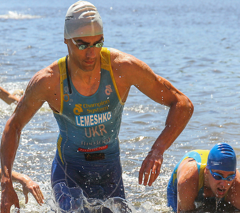 Triathleten kommen aus dem Wasser. Sie sind im Wettkampf und haben die Disziplin Schwimmen beendet.