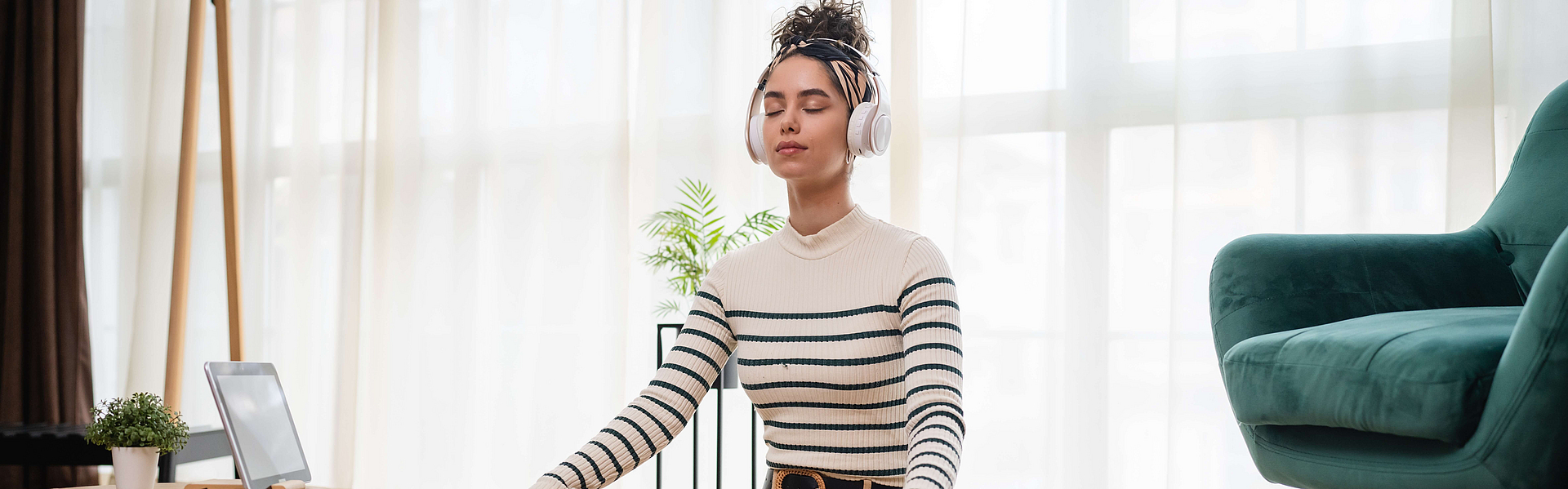 Frau sitzt aufrecht mit zufriedenem Gesicht auf dem Boden und hört Musik