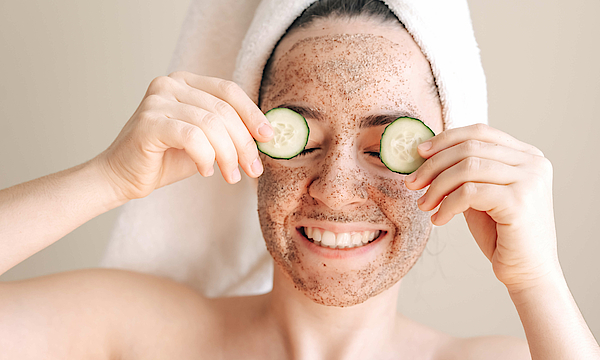Eine Frau die entspannt nach der Dusche eine Gesichtsmaske aufträgt.
