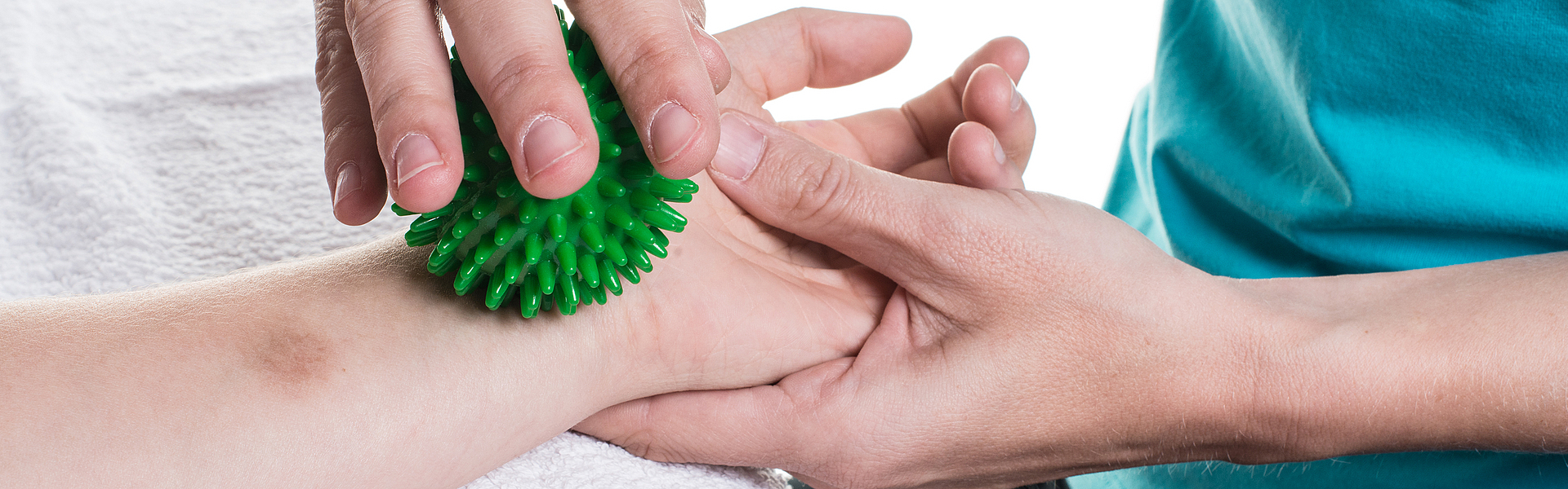 Die Ergotherapie zählt zu den Heilmitteln. Ein Therapaut behandelt den Arm eines Patienten mit dem Igel-Ball.