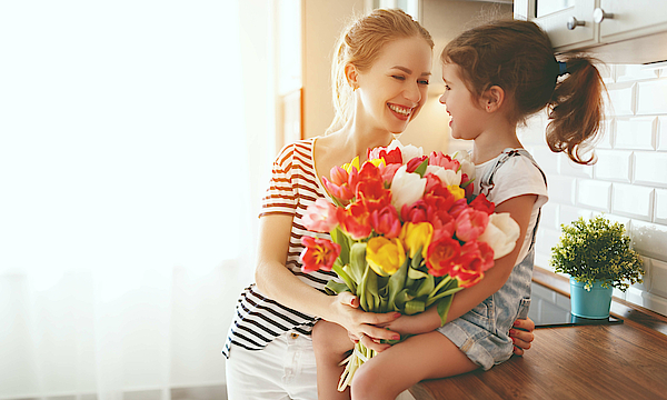 Frau schenkt dem Kind einen Blumenstrauß.