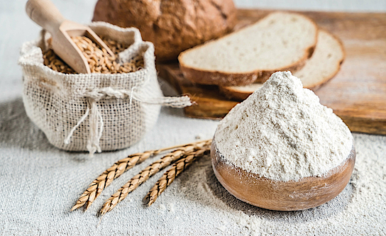 Auf einem Tisch stehen Brot, Korn und Mehl.