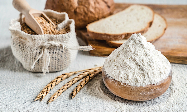 Auf einem Tisch stehen Brot, Korn und Mehl.