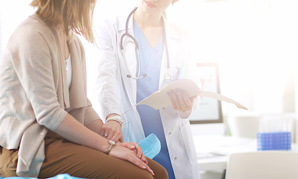 Ärztin und Patientin diskutieren über etwas, während sie am Tisch sitzen.