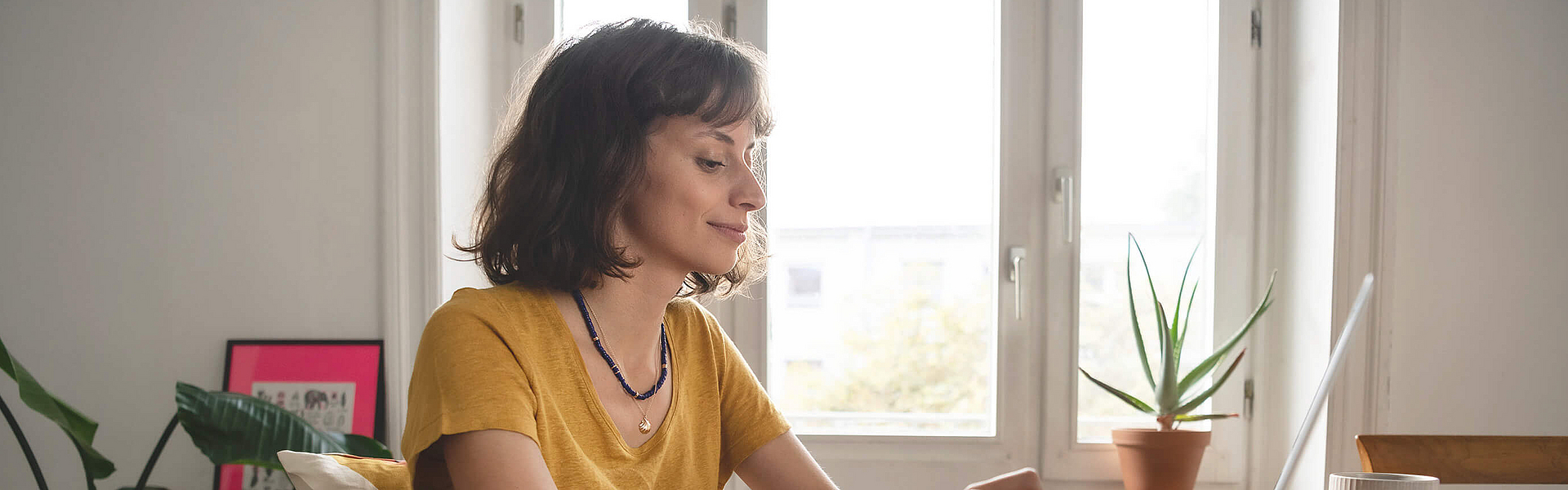 Junge selbstständige Frau sitzt am Laptop sie ist mhplus Mitglied. Sie verlässt sich auf einen starken Partner mhplus für Selbständige.
