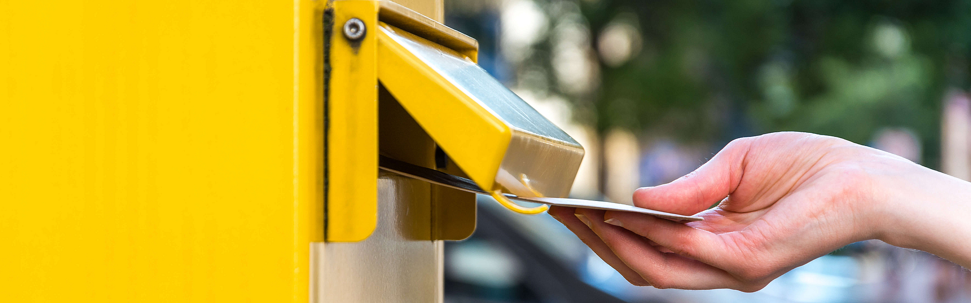Einen Brief in einen deutschen gelben Briefkasten werfen.