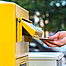 Einen Brief in einen deutschen gelben Briefkasten werfen.