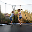 Geschwister amüsieren sich beim Springen auf Trampolin.
